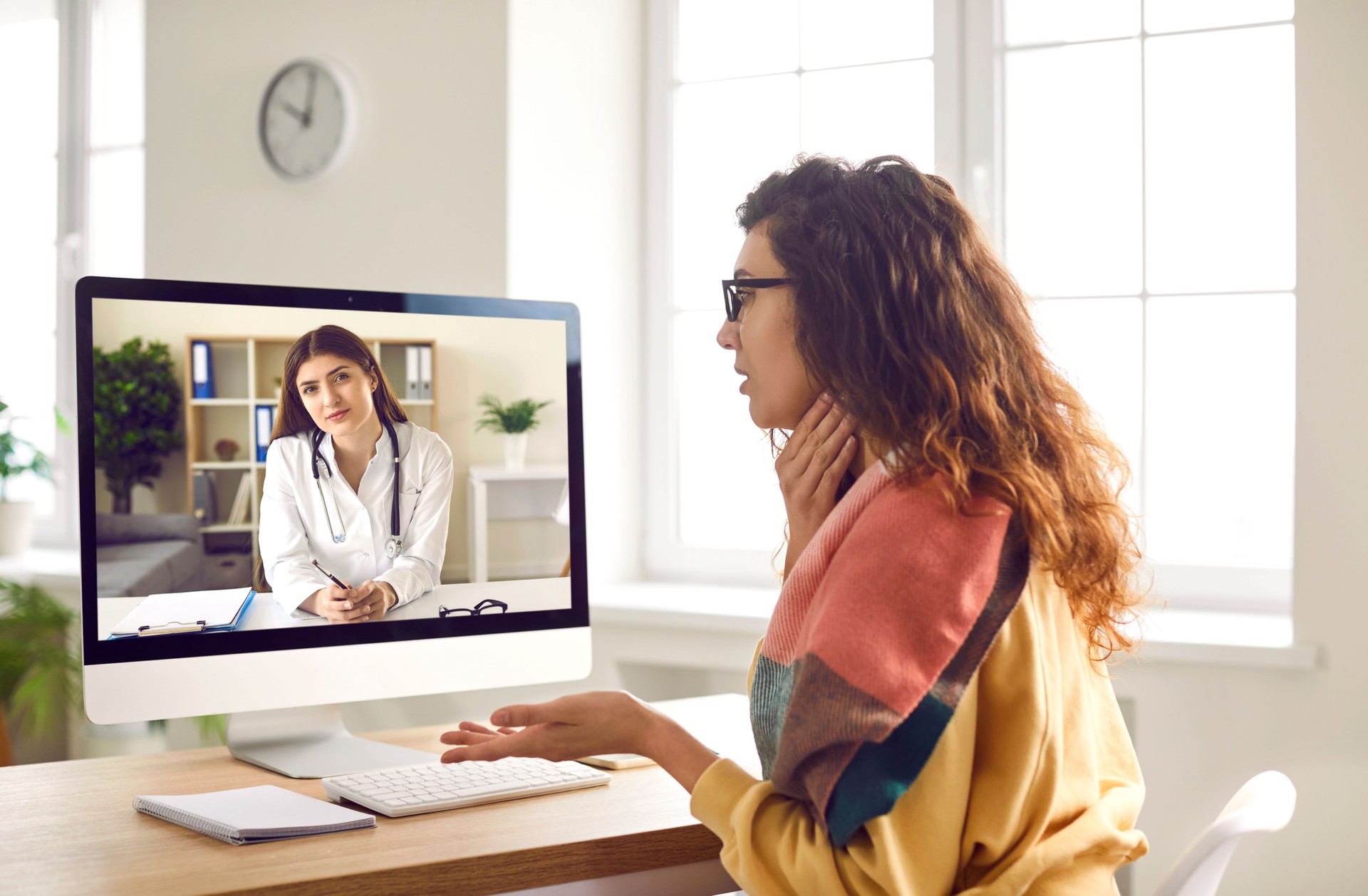 Woman with sore throat having medical consultation with online doctor via video call